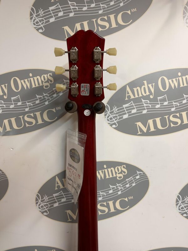 A red guitar with a logo in front of it.