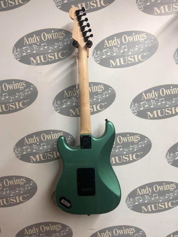 A green electric guitar hanging on a wall.