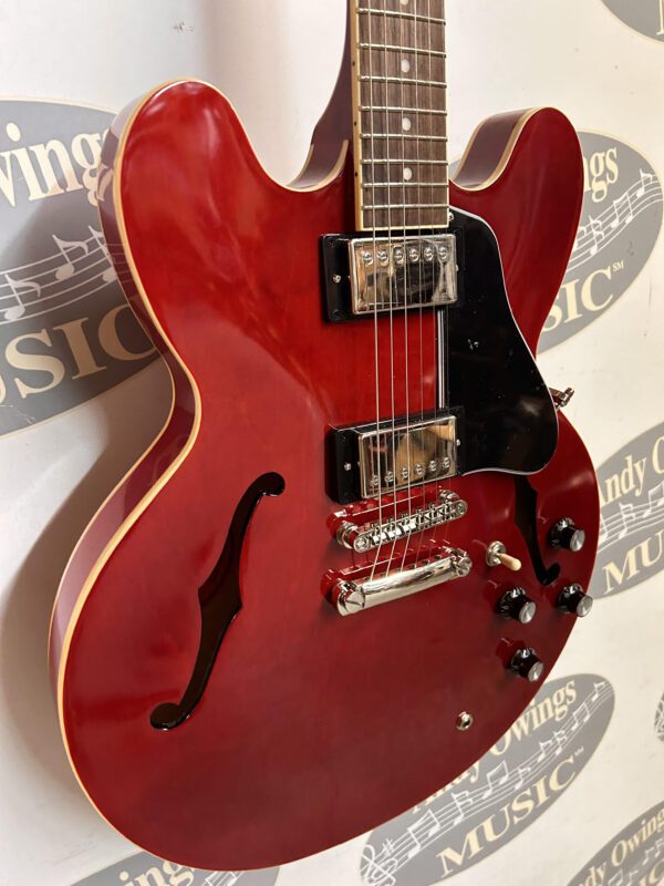 A red electric guitar hanging on a wall.