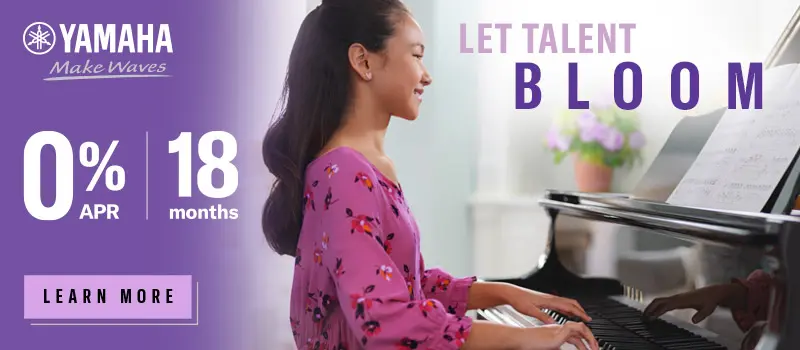 Small girl playing piano, smiling at the camera