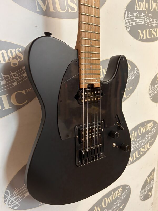 A black electric guitar hanging on a wall.