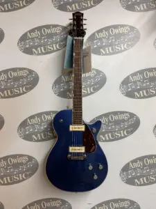 A blue electric guitar hanging on a wall.