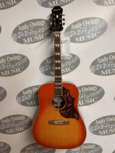 An Epiphone HummingBird Pro in front of a music store.