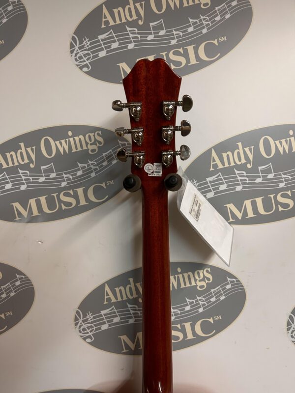 A red guitar with a tag on it.