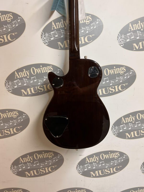 A guitar with a logo on it hanging on a wall.