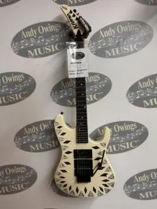 A white electric guitar with a tag on it.